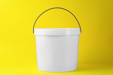 Photo of One plastic bucket with lid on yellow background