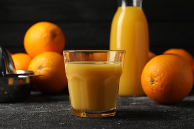 Tasty fresh oranges and juice on black table, closeup