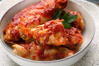 Photo of Delicious stuffed cabbage rolls cooked with homemade tomato sauce in bowl, closeup