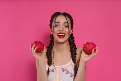 Young woman with fresh pitahayas on pink background. Exotic fruit