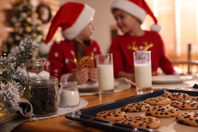 Photo of Cute little children with delicious Christmas cookies at home, focus on pastry