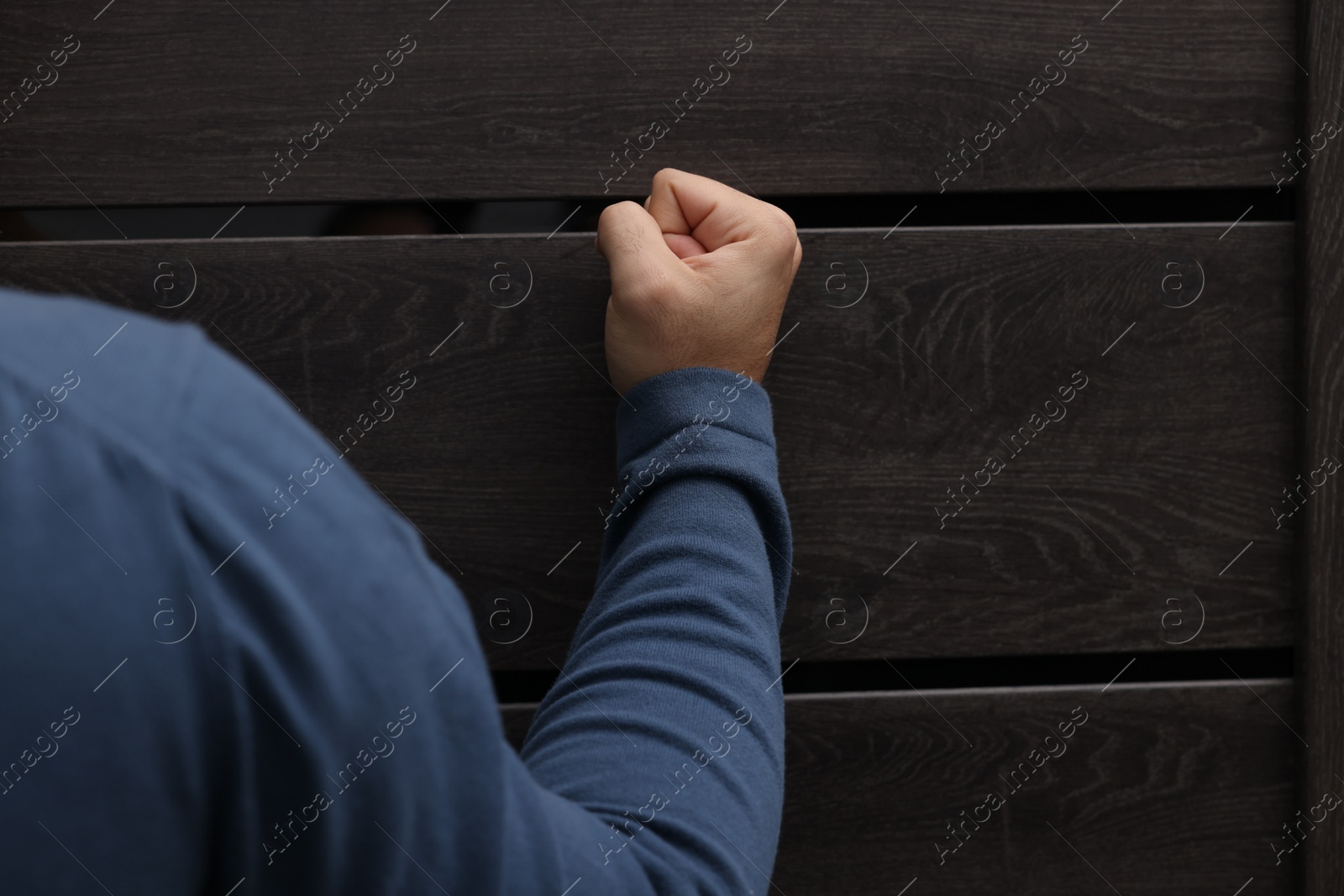 Photo of Collection agent knocking on wooden door, closeup