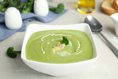 Photo of Delicious broccoli cream soup served on grey marble table