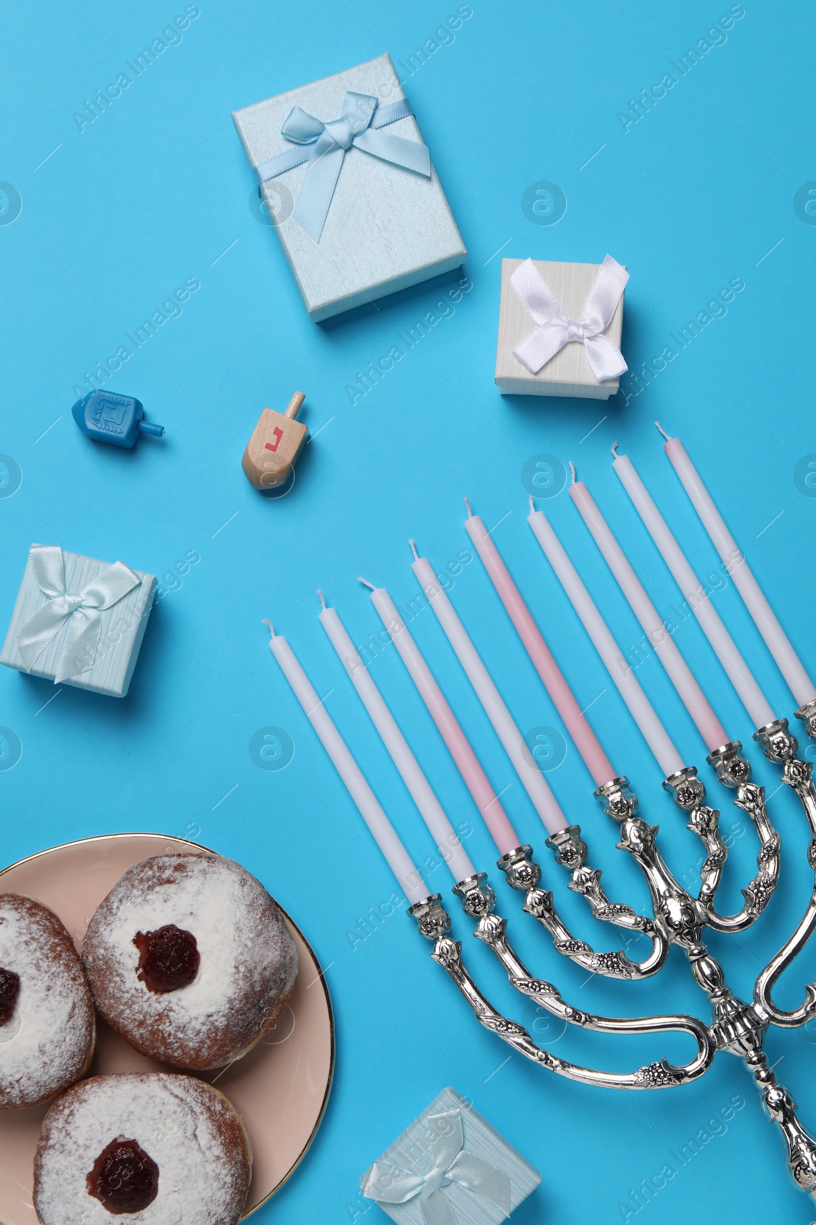 Photo of Flat lay composition with Hanukkah menorah and donuts on light blue background