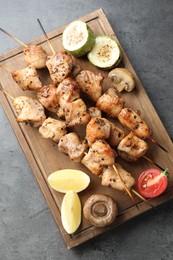 Delicious shish kebabs with vegetables and lemon on grey table, top view