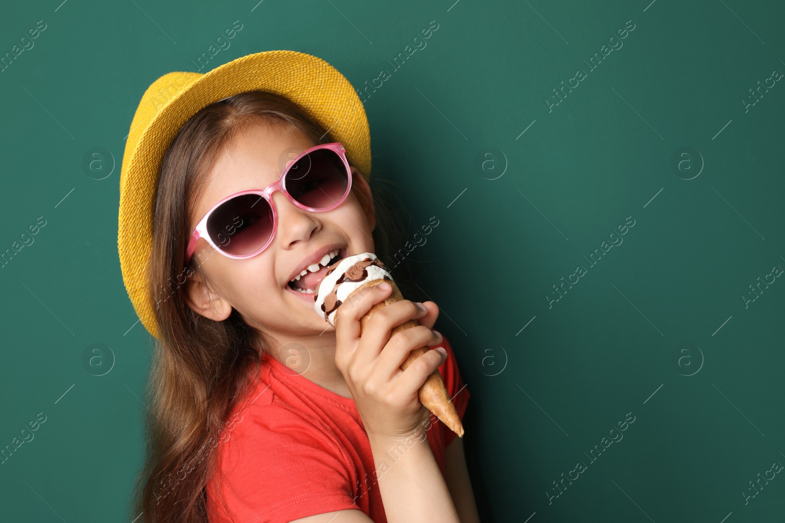 Photo of Cute little girl with delicious ice cream against color background, space for text