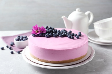 Plate with tasty blueberry cake on light grey table