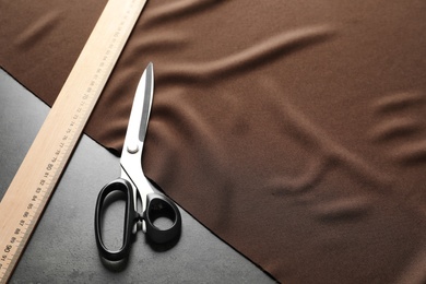 Photo of Scissors, ruler and fabric on grey background. Tailoring equipment