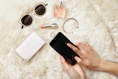 Photo of Woman making photo of cosmetics and accessories with mobile phone, flat lay. Beauty blogger