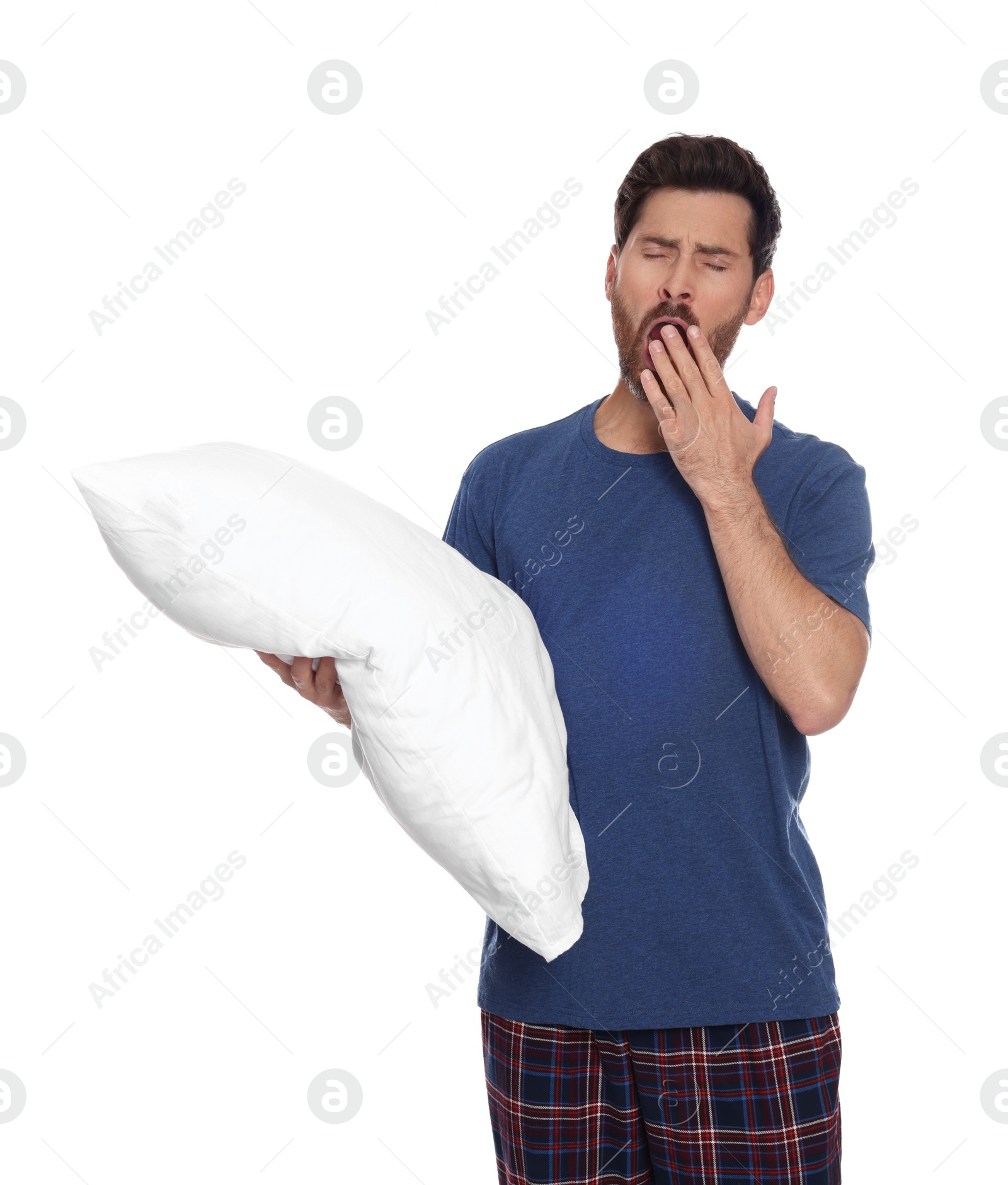 Photo of Tired man with pillow yawns on white background