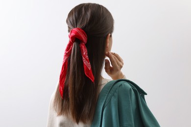 Young woman with stylish red bandana on light background, back view