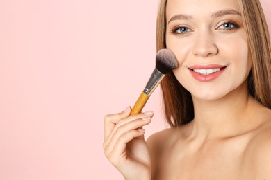 Photo of Portrait of beautiful young woman with makeup brush on color background. Space for text