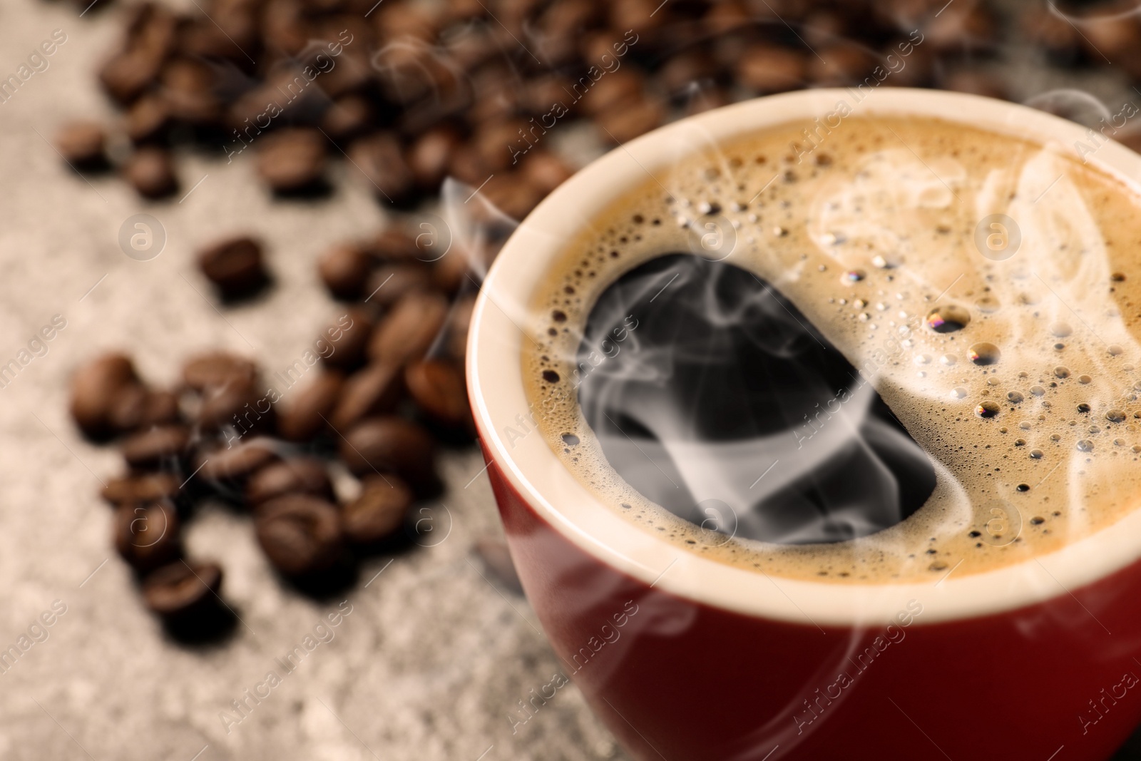 Image of Cup of aromatic hot coffee and beans on grey table, closeup. Space for text