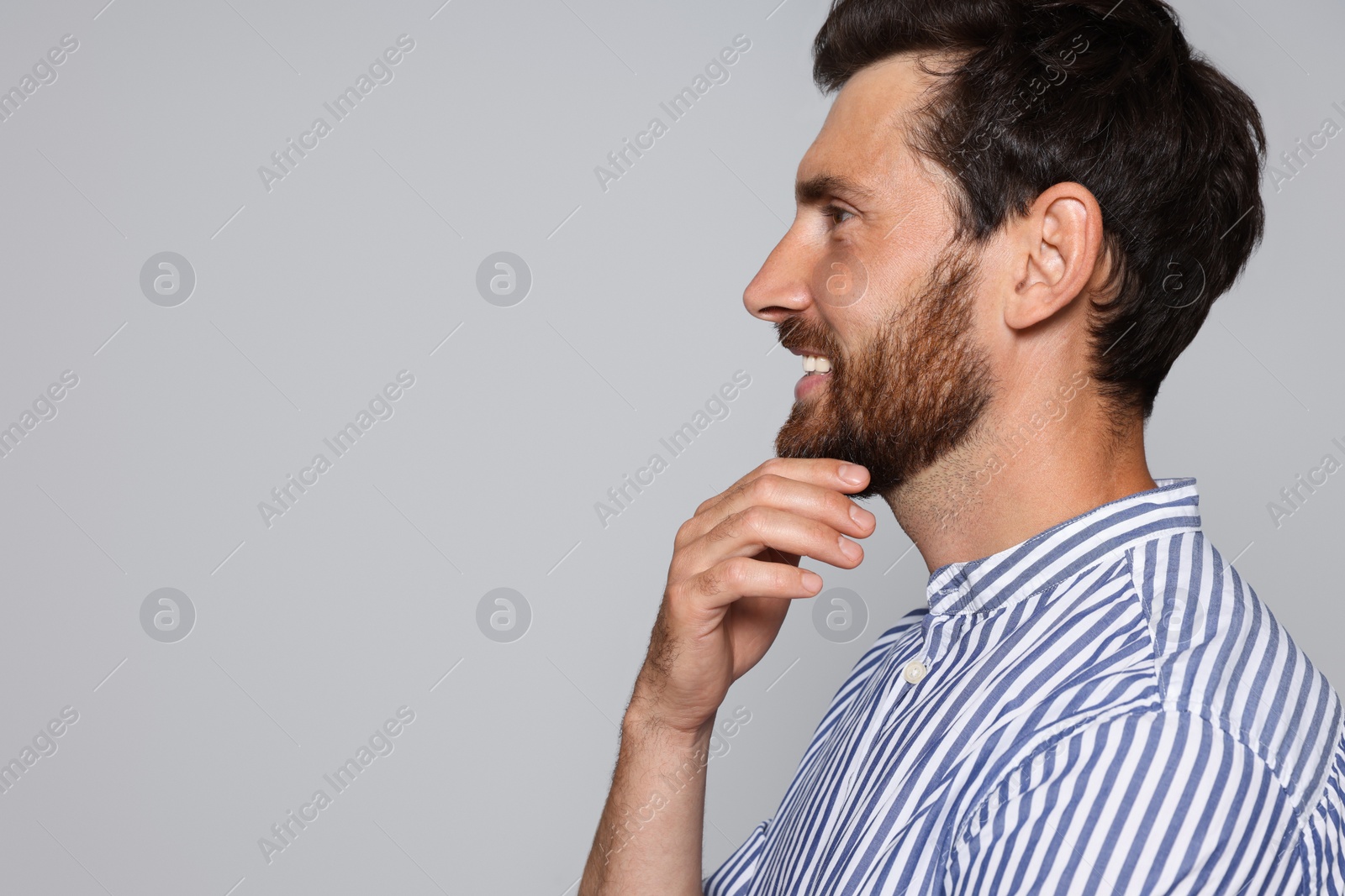 Photo of Profile portrait of smiling bearded man on grey background. Space for text