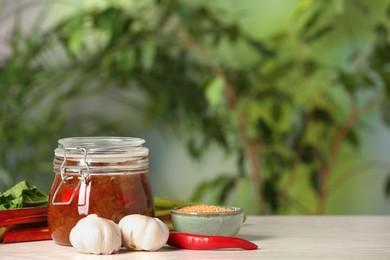 Tasty rhubarb sauce and ingredients on white table against blurred background , space for text