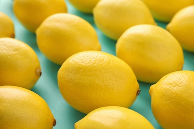 Photo of Many fresh lemons on turquoise background, closeup