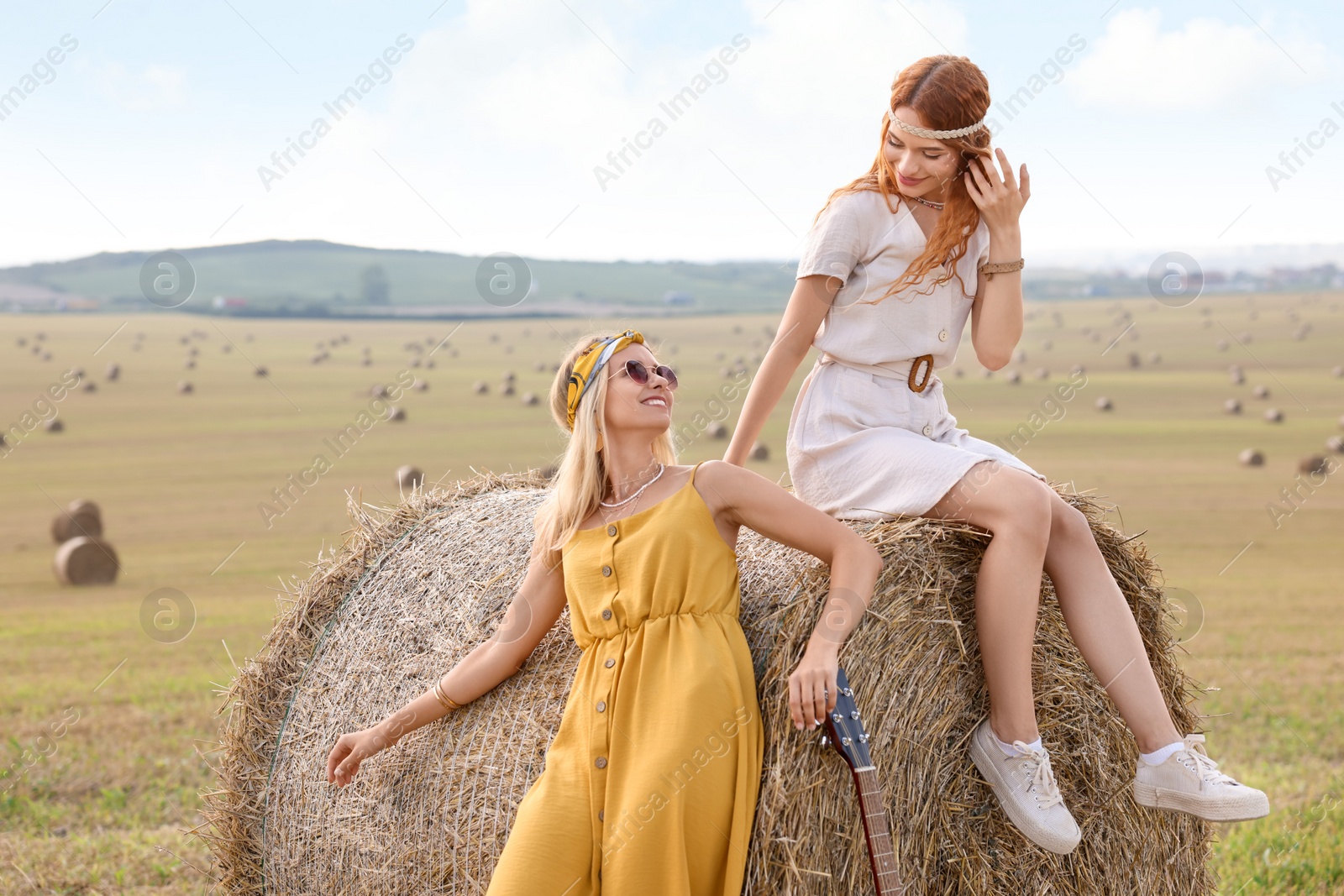 Photo of Beautiful happy hippie women with guitar in field