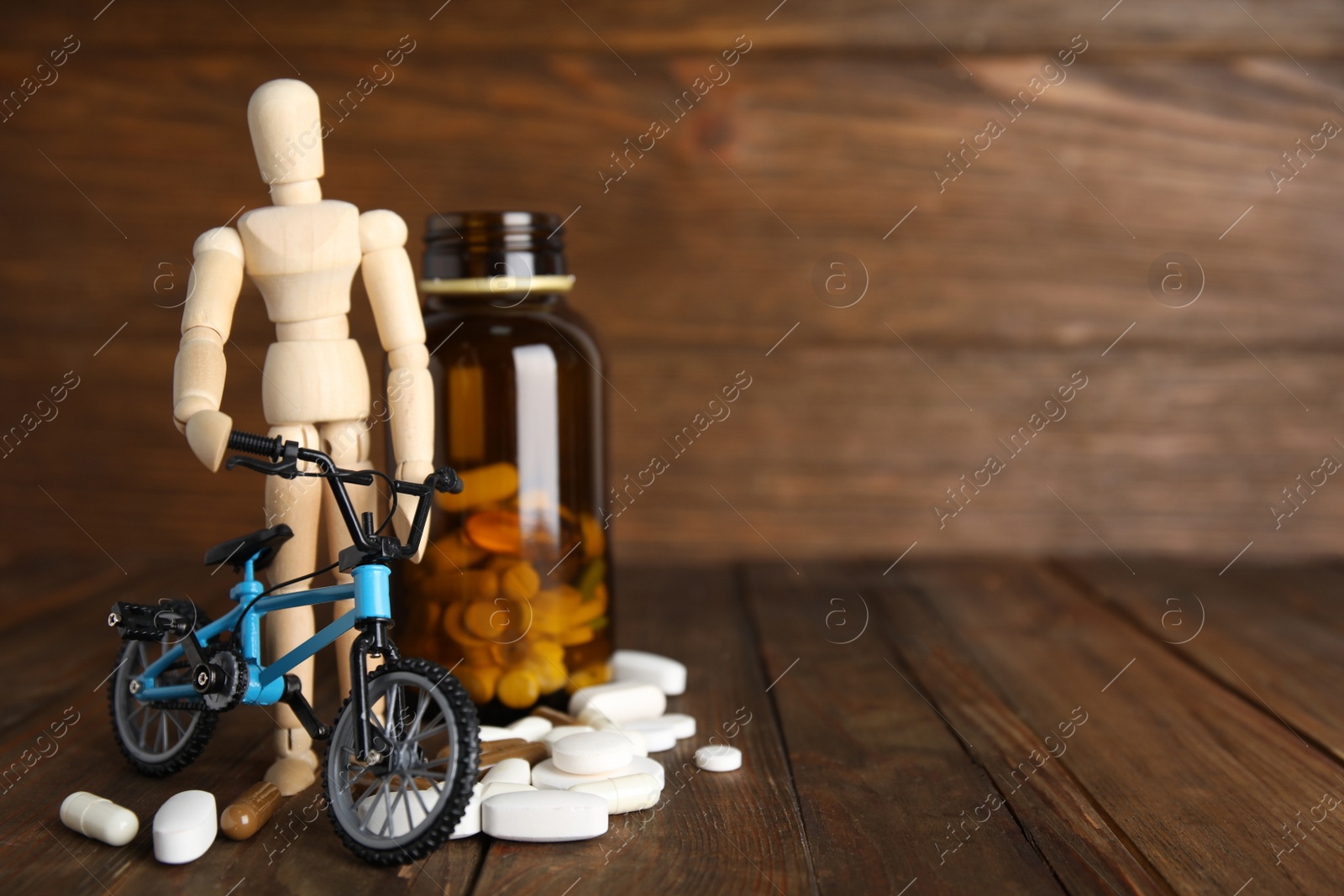 Photo of Pills, sportsman and bike model on wooden background, space for text. Using doping in cycling sport concept