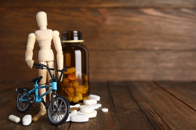 Pills, sportsman and bike model on wooden background, space for text. Using doping in cycling sport concept