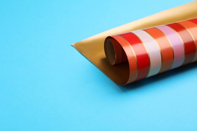 Photo of Roll of striped paper on light blue background, closeup. Space for text