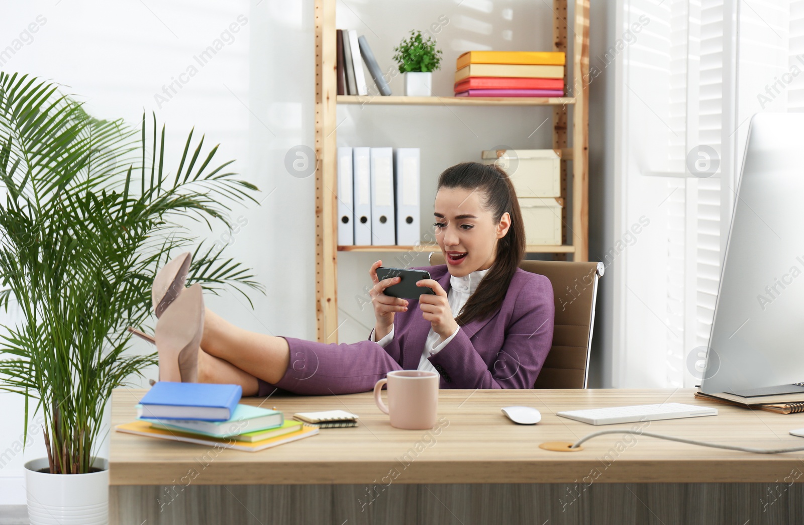 Photo of Lazy employee using smartphone at table in office