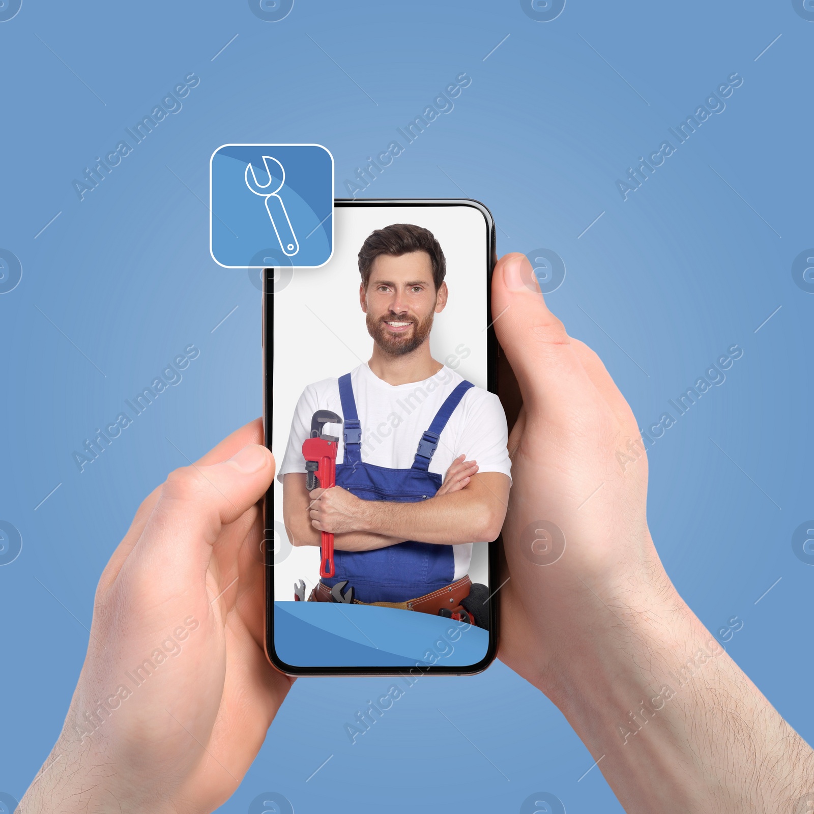 Image of Find plumber. Man using mobile phone on light blue background, closeup. Specialist looking out of gadget