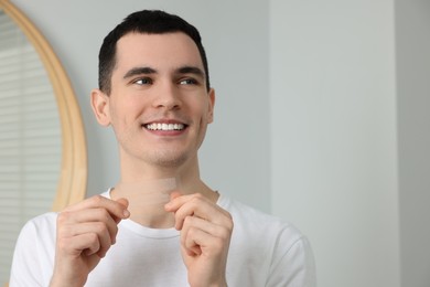 Photo of Young man with whitening strips indoors. Space for text