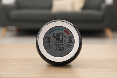 Photo of Digital hygrometer with thermometer on wooden table in room