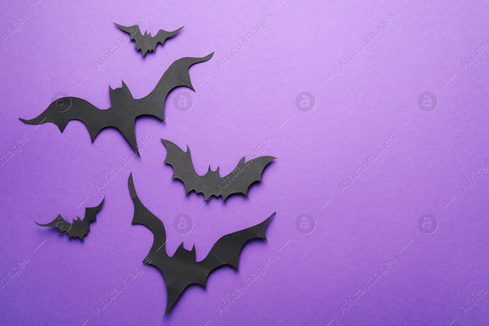 Photo of Paper bats and space for text on purple background, flat lay. Halloween decor