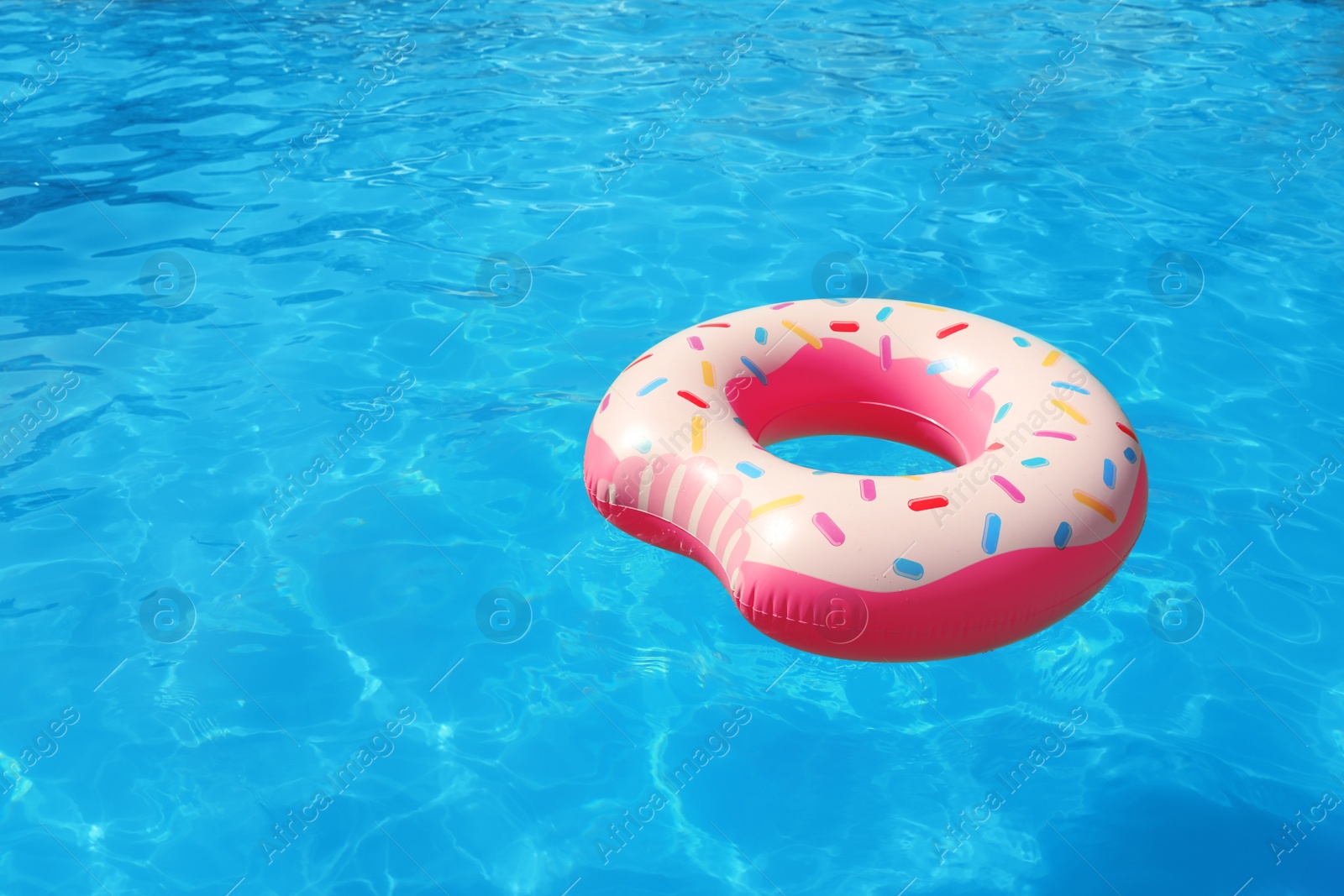 Photo of Inflatable ring floating in swimming pool on sunny day. Space for text