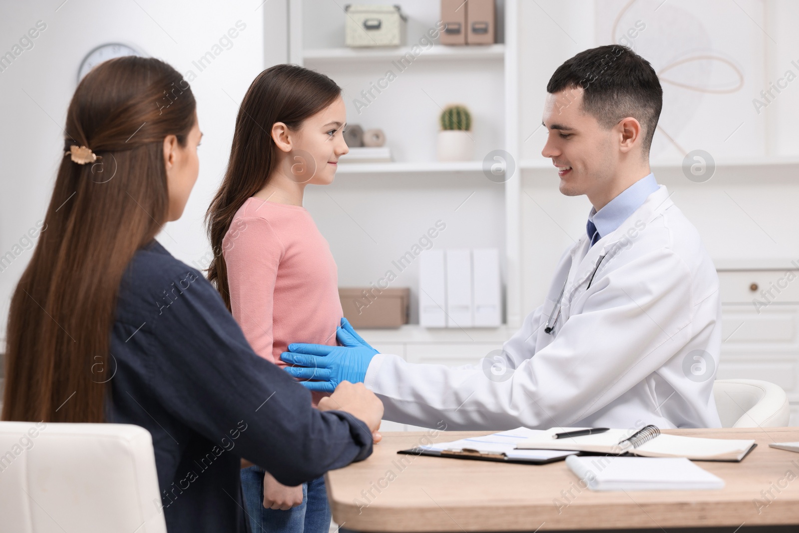 Photo of Gastroenterologist examining girl with stomach ache in clinic