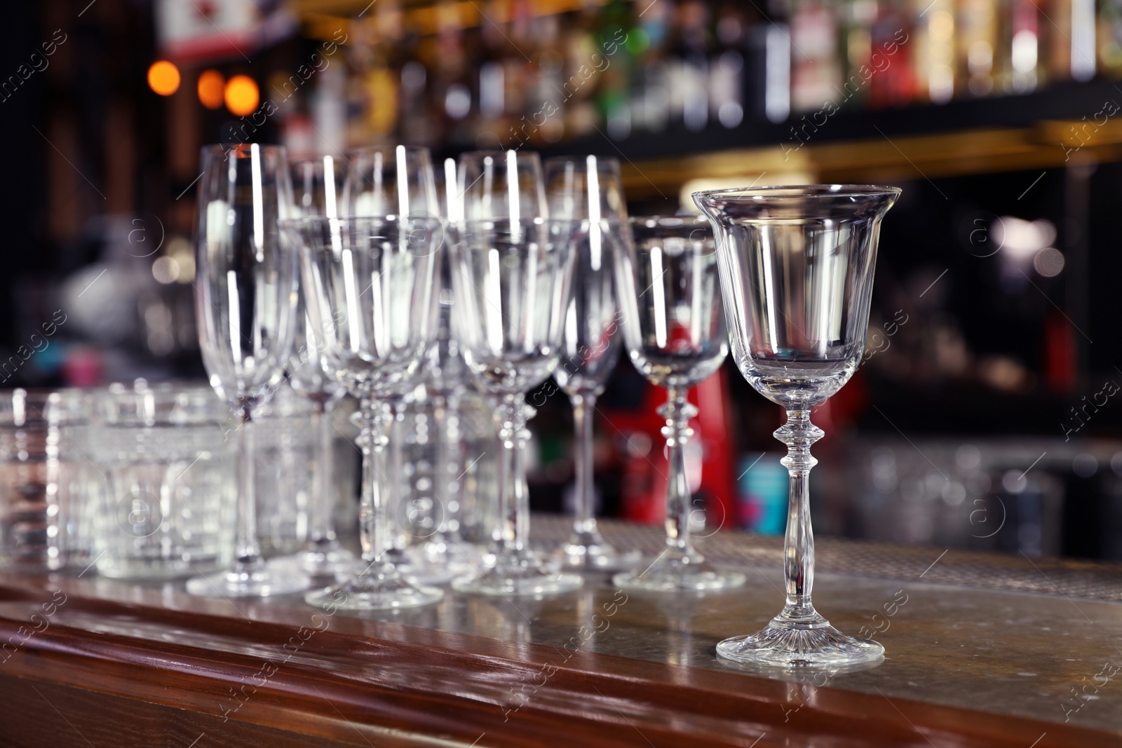 Photo of Different empty clean glasses on counter in bar