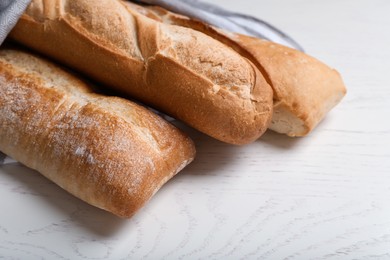 Photo of Different tasty baguettes on white wooden table, closeup