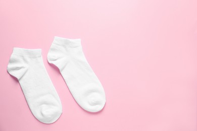 Photo of Pair of white socks on pink background, flat lay. Space for text