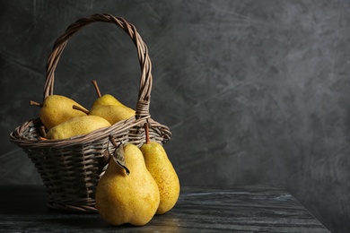 Photo of Basket of fresh ripe pears on table against gray background with space for text