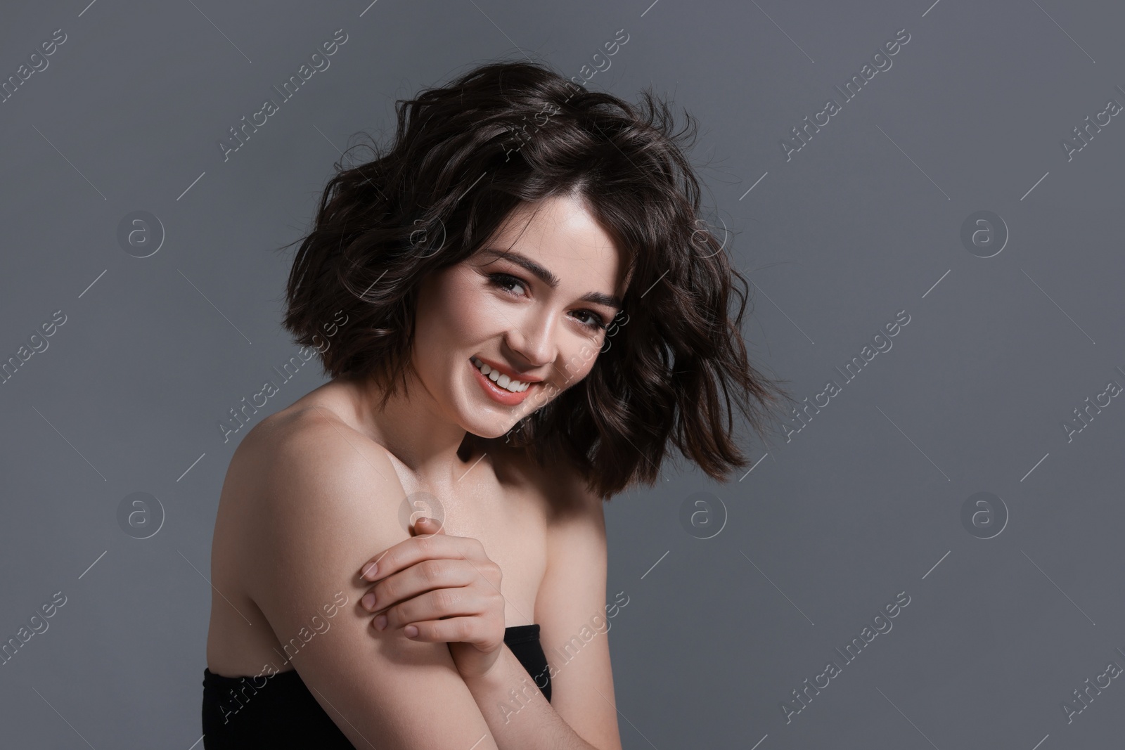 Photo of Portrait of beautiful young woman with wavy hairstyle on grey background. Space for text