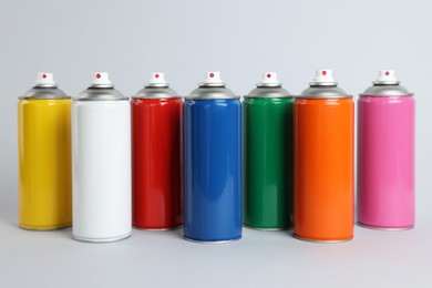 Colorful cans of spray paints on light grey background