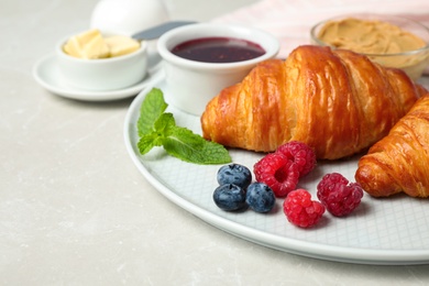 Photo of Tasty breakfast with croissants served on light grey marble table, closeup