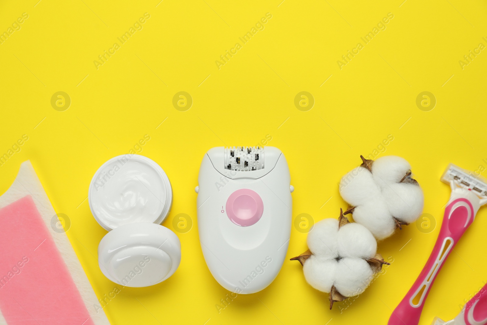 Photo of Different epilation products and fluffy cotton flowers on yellow background, flat lay. Space for text