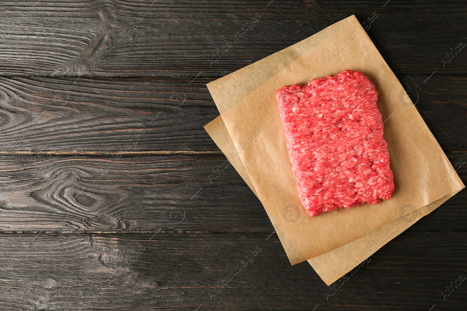 Photo of Fresh raw minced meat on black wooden table, top view. Space for text