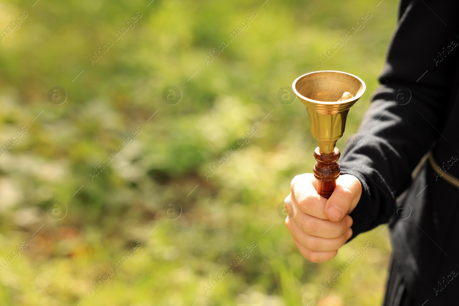 Photo of Pupil holding school bell outdoors on sunny day, closeup. Space for text