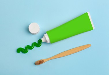 Tube of aloe toothpaste and toothbrush on light blue background, flat lay