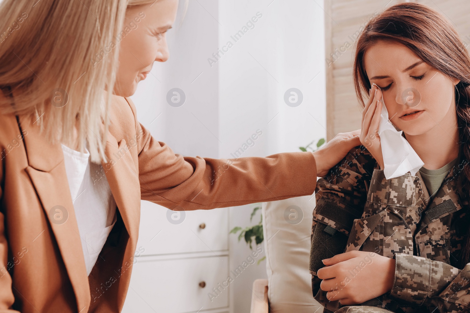 Photo of Psychologist supporting sad female military officer indoors