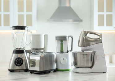 Photo of Set of modern home appliances on white marble table in kitchen