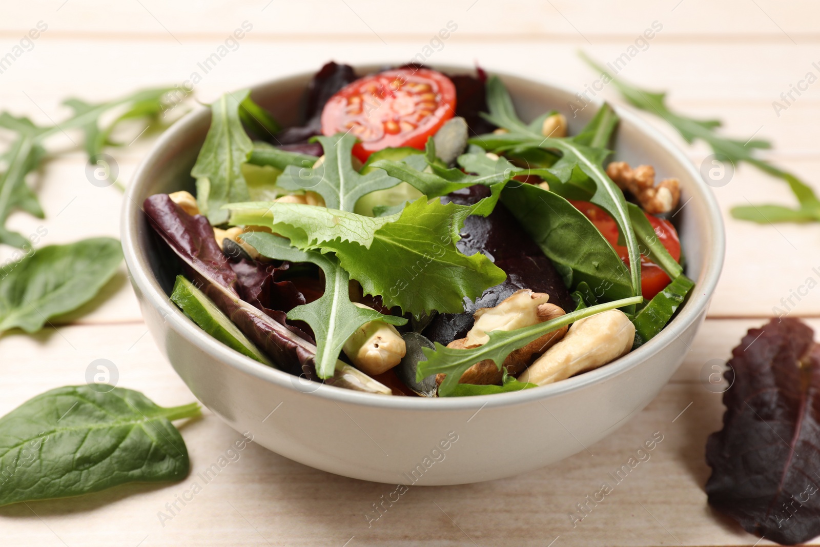 Photo of Tasty fresh vegetarian salad on light wooden table, closeup