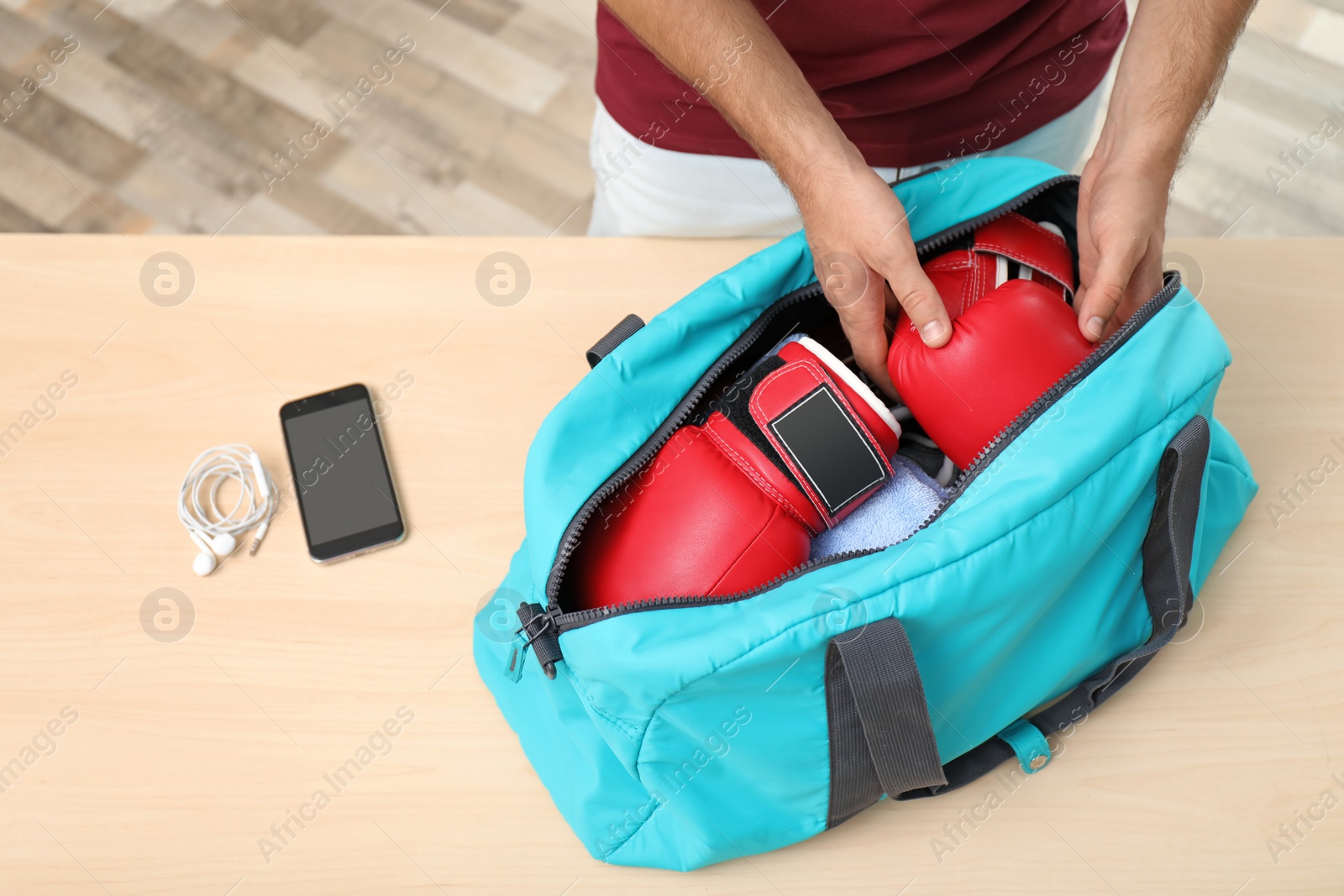 Photo of Young man packing sports bag on table