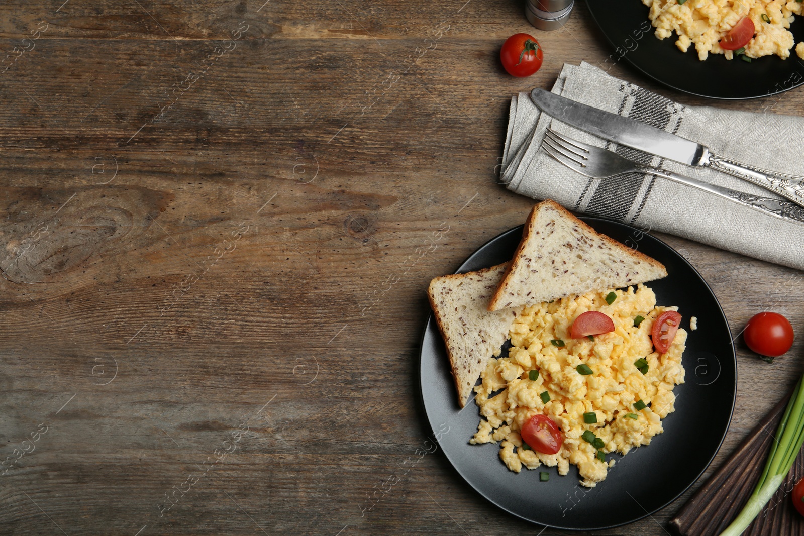 Photo of Tasty scrambled eggs served on wooden table, flat lay. Space for text
