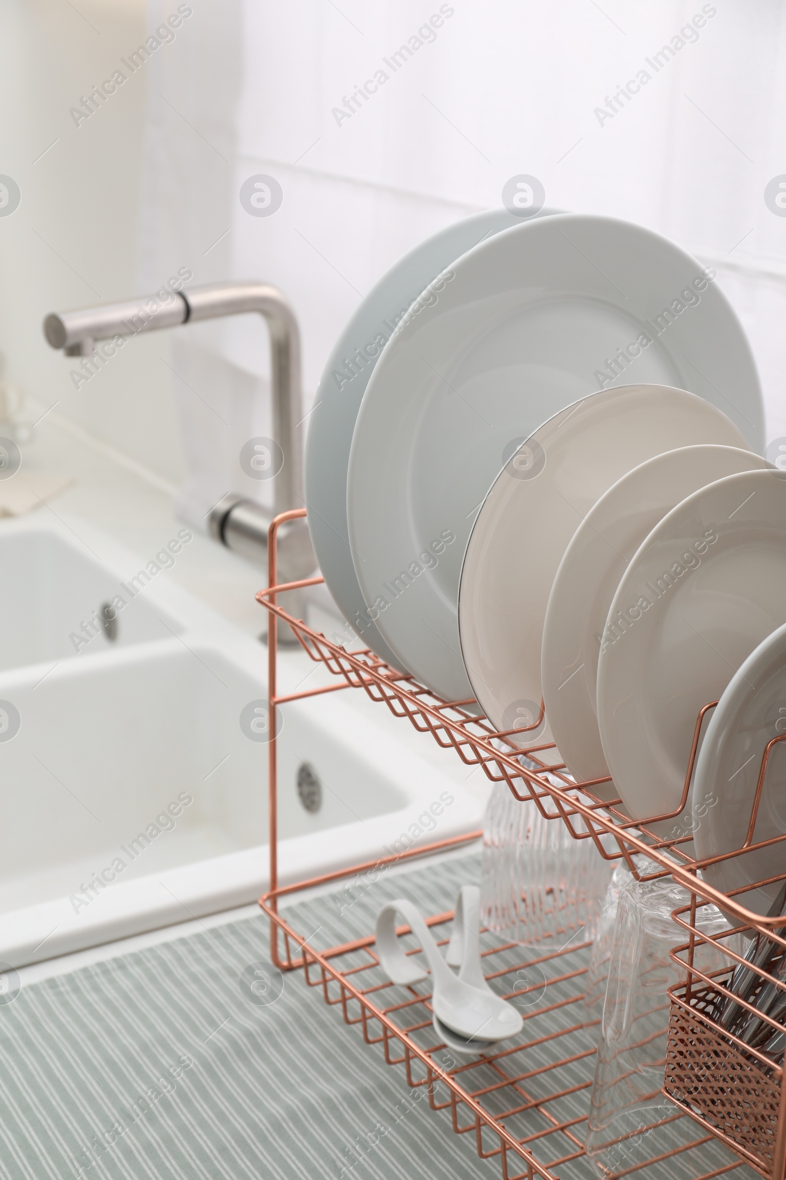 Photo of Drying rack with clean dishes on countertop near sink in kitchen