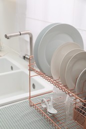 Drying rack with clean dishes on countertop near sink in kitchen