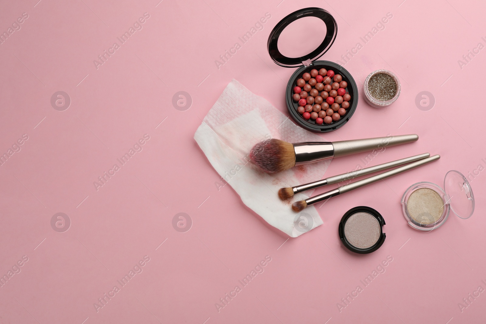 Photo of Dirty wet wipe, brushes and cosmetic on light pink background, flat lay. Space for text